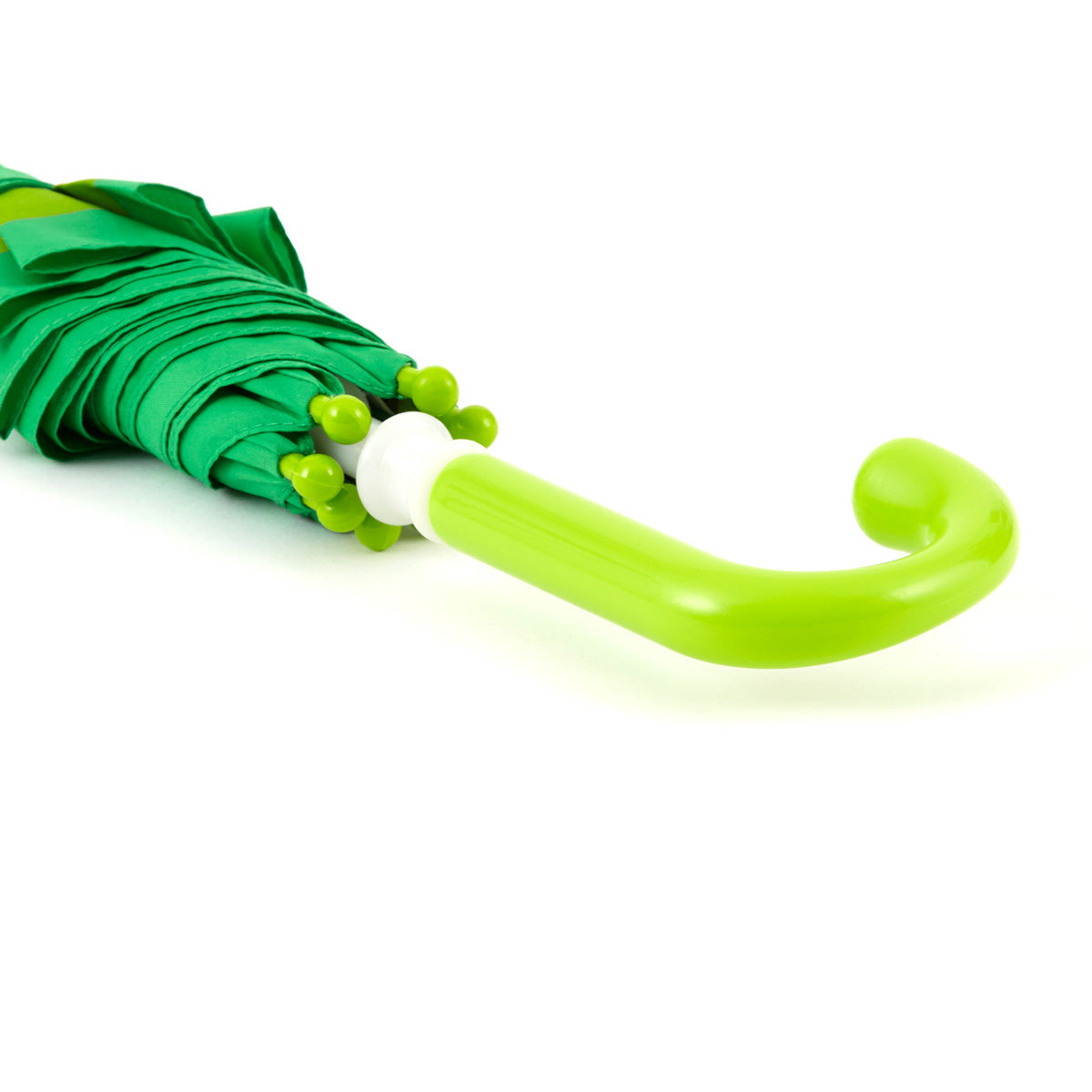 close up image of the handle of a brightly colored childrens umbrella in a kelly green frog design with a big red smile, lime green trim and pop-up eyeballs on top. matching lime green curved crook handle.