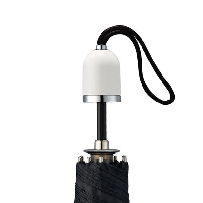 straight on view of a handmade manual open compact luxury umbrella with a glossy piano finish bright white handle, detachable waxed cotton wrist strap, Teflon-coated fine denier woven black polyester twill canopy, chrome trim, Trilobe aircraft aluminum shaft, fiberglass ribs, and a reflective strap embroidered with “ShedRain Stratus" in its free-standing canvas case with a close-up of the handle.